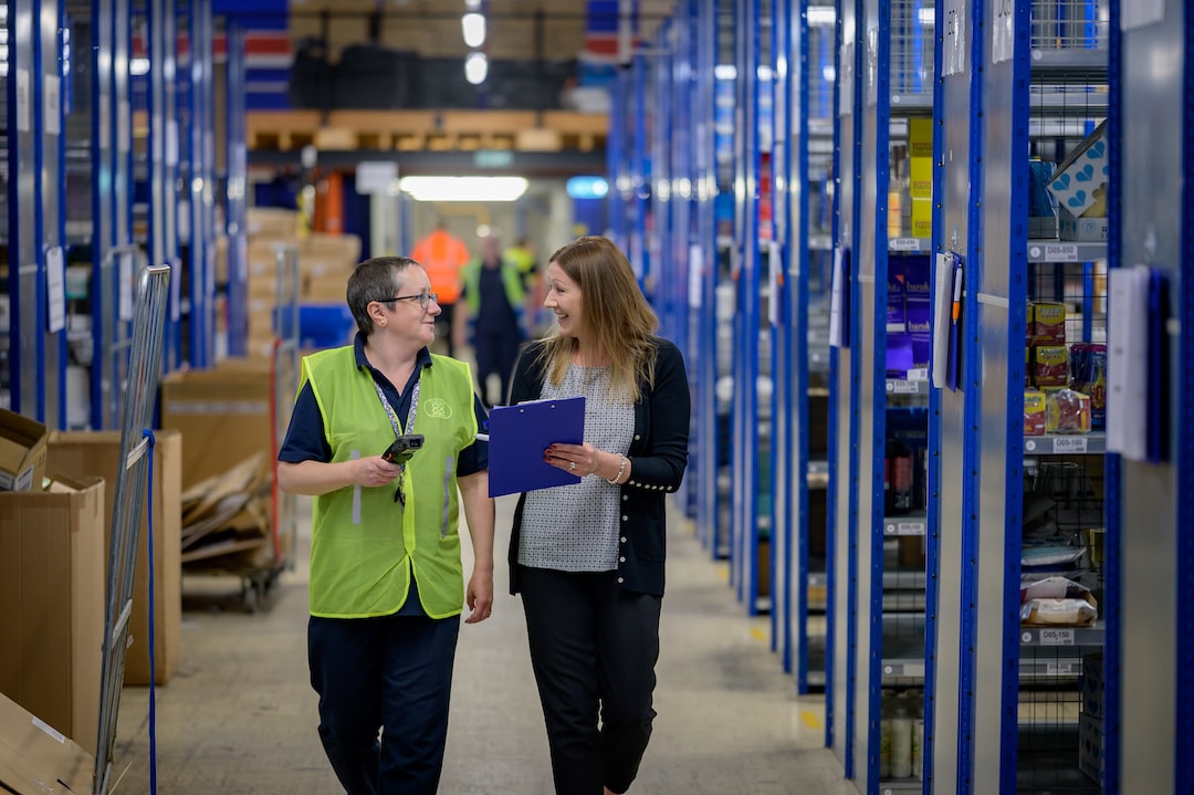 Two people walking and talking together down a warehouse aisle.