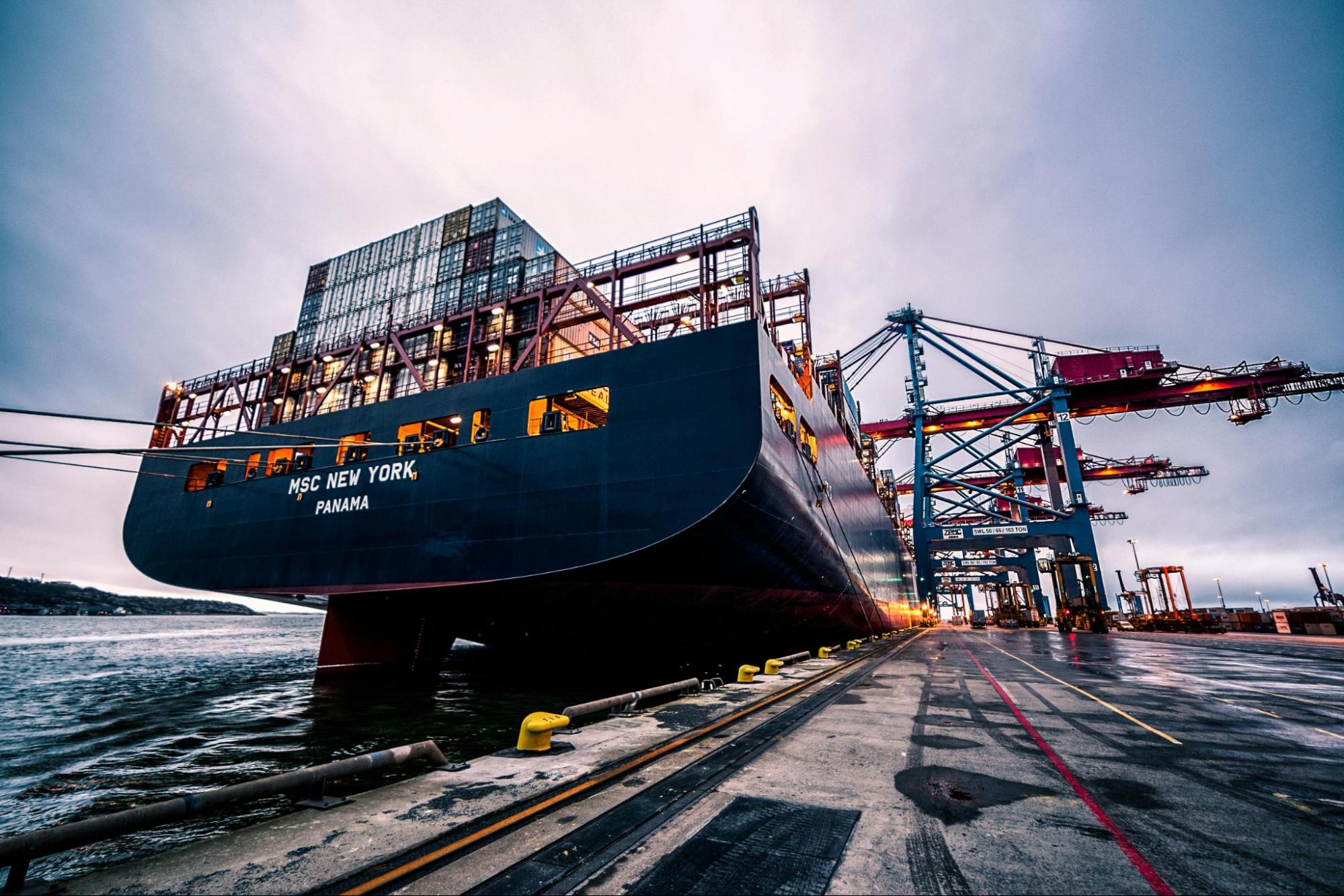 A large cargo ship sitting against a dock, with ‘MSC New York, Panama’ across its front.